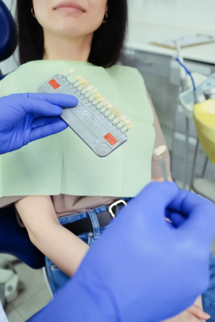 Dentist performing shade and colour consultation with a patient — the precise clinical assessment used before dental implant prosthesis and cosmetic treatment in Turkey